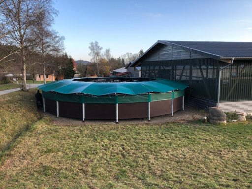 Führanlage 14,4 Meter für 6 Pferde in Sockach Runder, mit einer grünen Abdeckung versehener Pool neben einem Gebäude und Rasenfläche.